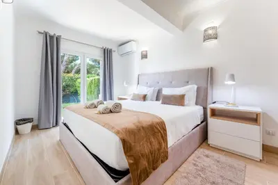 a white bedroom with a large bed and a window at Apartamento Pine by Algarve Holidays in Roja- Pé