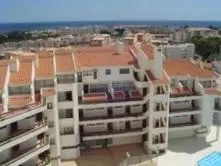 a white apartment building with the ocean in the background at Apartamento Ariadna in Albufeira