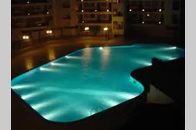 a large swimming pool with blue lighting in a building at Apartamento Ariadna in Albufeira