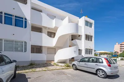a white building with a car parked in front of it at Seaside Charm Flat w/ Balcony by HostWise in Albufeira