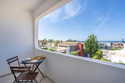 a balcony with a table and chairs and a window at Seaside Charm Flat w/ Balcony by HostWise in Albufeira