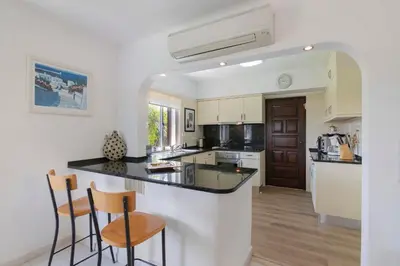 a kitchen with a counter and two bar stools at Villa Rose in Albufeira