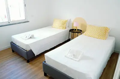 two beds in a room with white walls at Dona Maria Guest House in Faro