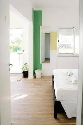 a bedroom with a white bed and a green wall at Dona Maria Guest House in Faro