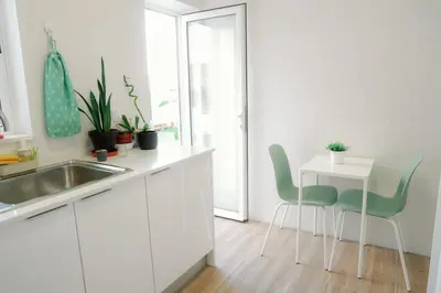 a kitchen with white cabinets and a table and chairs at Dona Maria Guest House in Faro