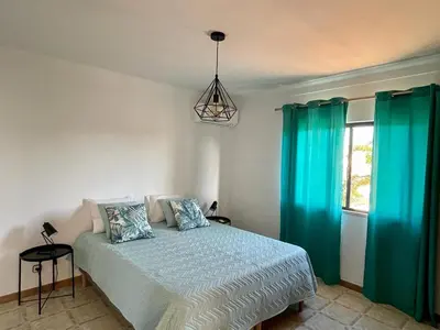 a bedroom with a bed with blue curtains at Vivenda Duas Sentinelas 42 in Quarteira