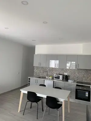 a white kitchen with a table and chairs in it at Casa Foka in Faro