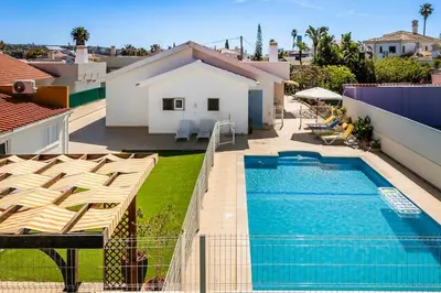 a patio with chairs and an umbrella and a pool at Solar do Castelo Villa with Pool in Albufeira
