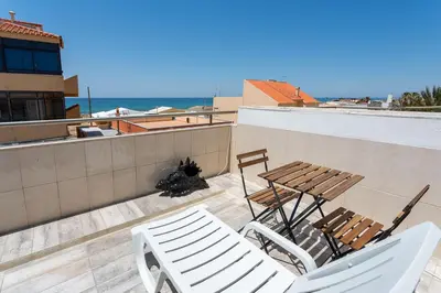 a patio with a table and chairs and the ocean at Blife Charlya private apartment at Faro beach in Faro