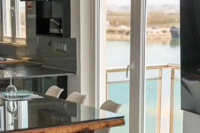 a kitchen with a glass table and a view of the water at Blife Charlya private apartment at Faro beach in Faro