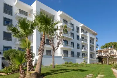 an apartment building with palm trees in front of it at Luz do Mar in Olhos de Água