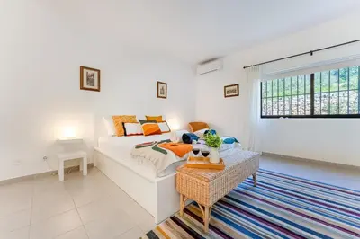 a white bedroom with a bed and a table at Casa Federica by Algarve Holidays in Santa Bárbara de Nexe