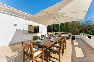 a patio with a wooden table and an umbrella at Casa Federica by Algarve Holidays in Santa Bárbara de Nexe