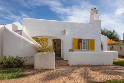 a church with a white building with yellow shutters at Sail Golf Vilamoura V3 in Quarteira