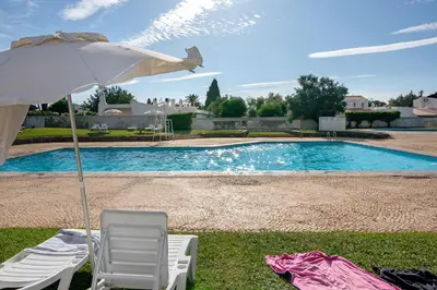 a chair and an umbrella next to a swimming pool at Sail Golf Vilamoura V3 in Quarteira