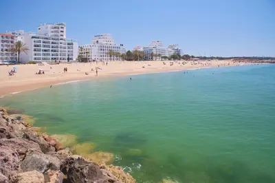 a beach with people in the water and buildings at 2 Bedroom by Quarteira Beach in Quarteira