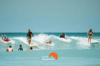 a group of people riding a wave on surfboards in the ocean at #283 Palmeira Gale by Home Holidays in Galé