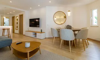 a living room with a table and chairs and a mirror at Luxury Garden House Apartment - Golf & Tennis Court & Pools in Albufeira