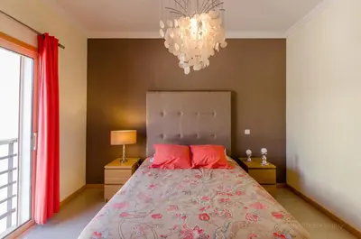 a bedroom with a bed with red pillows and a chandelier at Apartament Encosta Da Orada in Albufeira