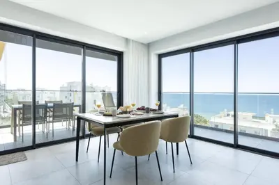 a dining room with a table and chairs and large windows at Terracos de Quarteira II Pearl by Real Properties in Quarteira