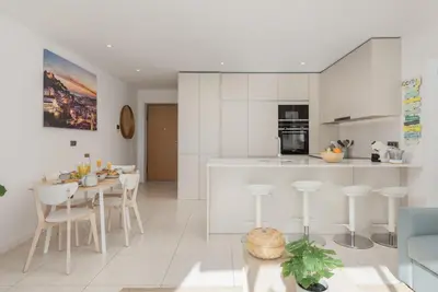 a kitchen and living room with white cabinets and a table at Terracos de Quarteira I Aqua by Real Properties in Quarteira