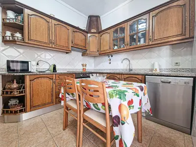 a kitchen with wooden cabinets and a table and chairs at Casa Bacalhau - Tunes - Jacuzzi - BY BEDZY in Tunes