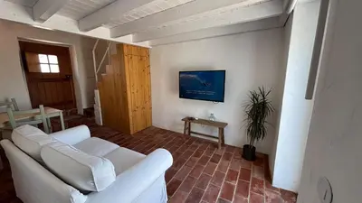 a living room with a white couch and a tv at Laranjeira 1 by AlmaAlgarvia in Santa Bárbara de Nexe