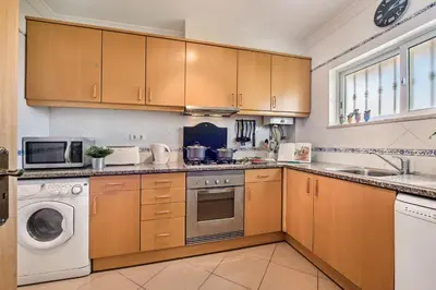 a kitchen with wooden cabinets and a washer and dryer at Apartment 1A Gale Garden by Algarve Villa Holidays in Albufeira