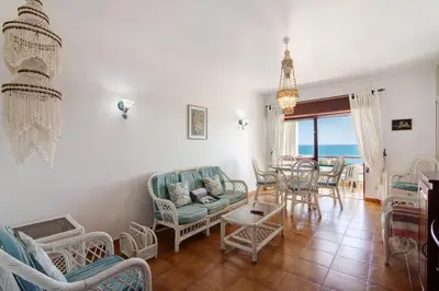 a living room with a table and chairs and the ocean at Beachfront Apartment T2 in Quarteira