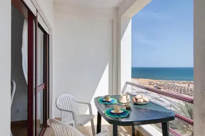 a balcony with a table and a view of the ocean at Beachfront Apartment T2 in Quarteira