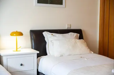 a bedroom with a bed with a black headboard and a night stand at Rosemary Apartment in Olhos de Água