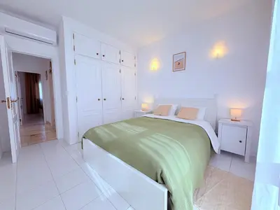 a white bedroom with a bed and two lamps on two tables at Casita 9 in Albufeira