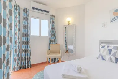 a bedroom with a bed and a chair and a mirror at #326 Vista Mar by Home Holidays in Albufeira