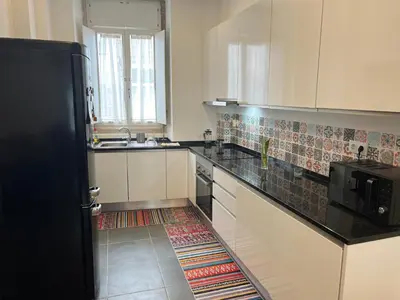 a kitchen with white cabinets and a black counter top at Train Station Guesthouse in Faro
