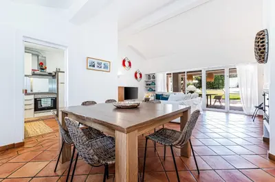 a kitchen and living room with a wooden table and chairs at Villa Falésia in Olhos de Água