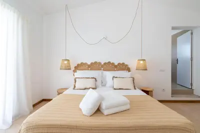 a white bedroom with a large bed with two pillows at Alma Invicta Albufeira in Albufeira