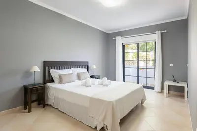 a bedroom with a large white bed and a window at Modern 2BR Quarteira Apartment in Quarteira
