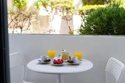 a table with a plate of food and two glasses of orange juice at Modern 2BR Quarteira Apartment in Quarteira