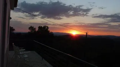 a sunset from the balcony of a house with two chairs at B&B Casa Encantada in Boliqueime