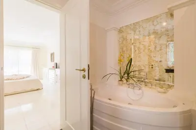 a white bathroom with a tub and a bedroom at Traumhaft schöne Villa mit Pool und Meerblick in Albufeira