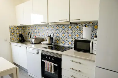 a kitchen with white cabinets and a black microwave at Casas Sao Luis in Faro