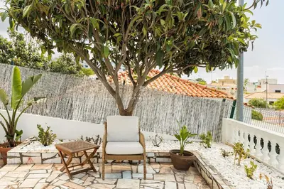 a chair and a table and a tree on a patio at Casa Bela Mar in Albufeira