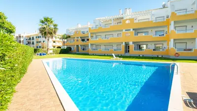 a swimming pool in front of a building at Falesia Marina in Quarteira