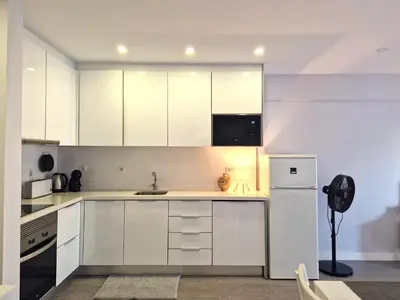 a white kitchen with a sink and a refrigerator at Quarteira flat AC balcony and view in Quarteira