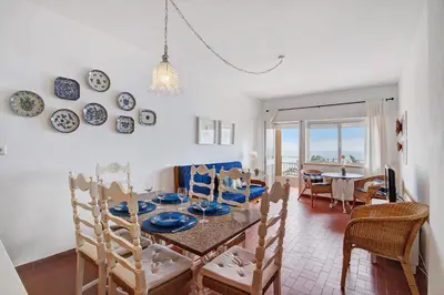 a dining room and living room with a table and chairs at Apartamento Mar Azul - Quarteira in Quarteira