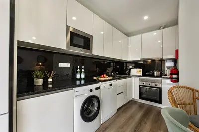 a kitchen with white cabinets and a washer and dryer at Stay Apartment in Faro