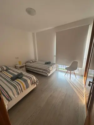 a bedroom with two beds and a chair in it at Modern apartment in Al-sakia Village in Quarteira