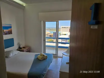 a bedroom with a bed and a view of a balcony at Blife Cerya private rooms at Faro beach in Faro