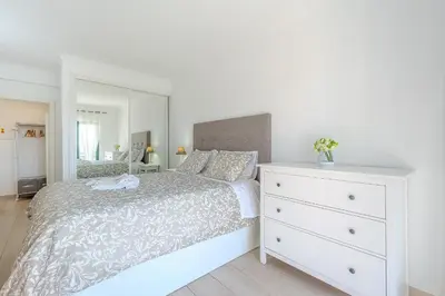 a bedroom with a white bed and a white dresser at Salgados Sunset and Sea View Apartment in Guia