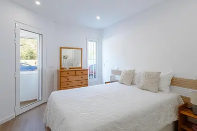 a bedroom with a bed with white sheets and a wooden cabinet at Albufeira Old Town Apartment in Albufeira